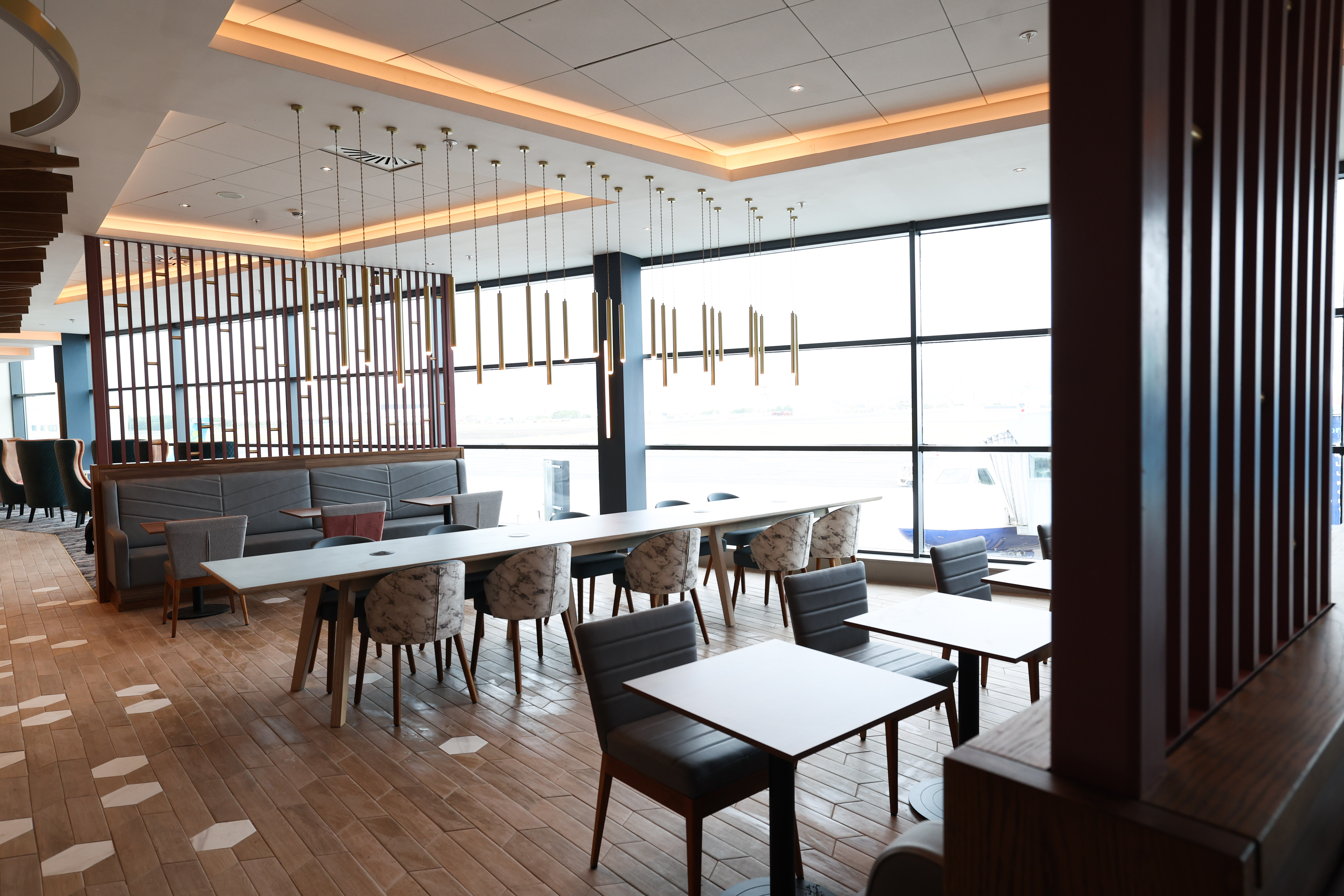 Spacious lounge dining area with wood floors and floor-to-ceiling windows at the Belfast Aspire Lounge.