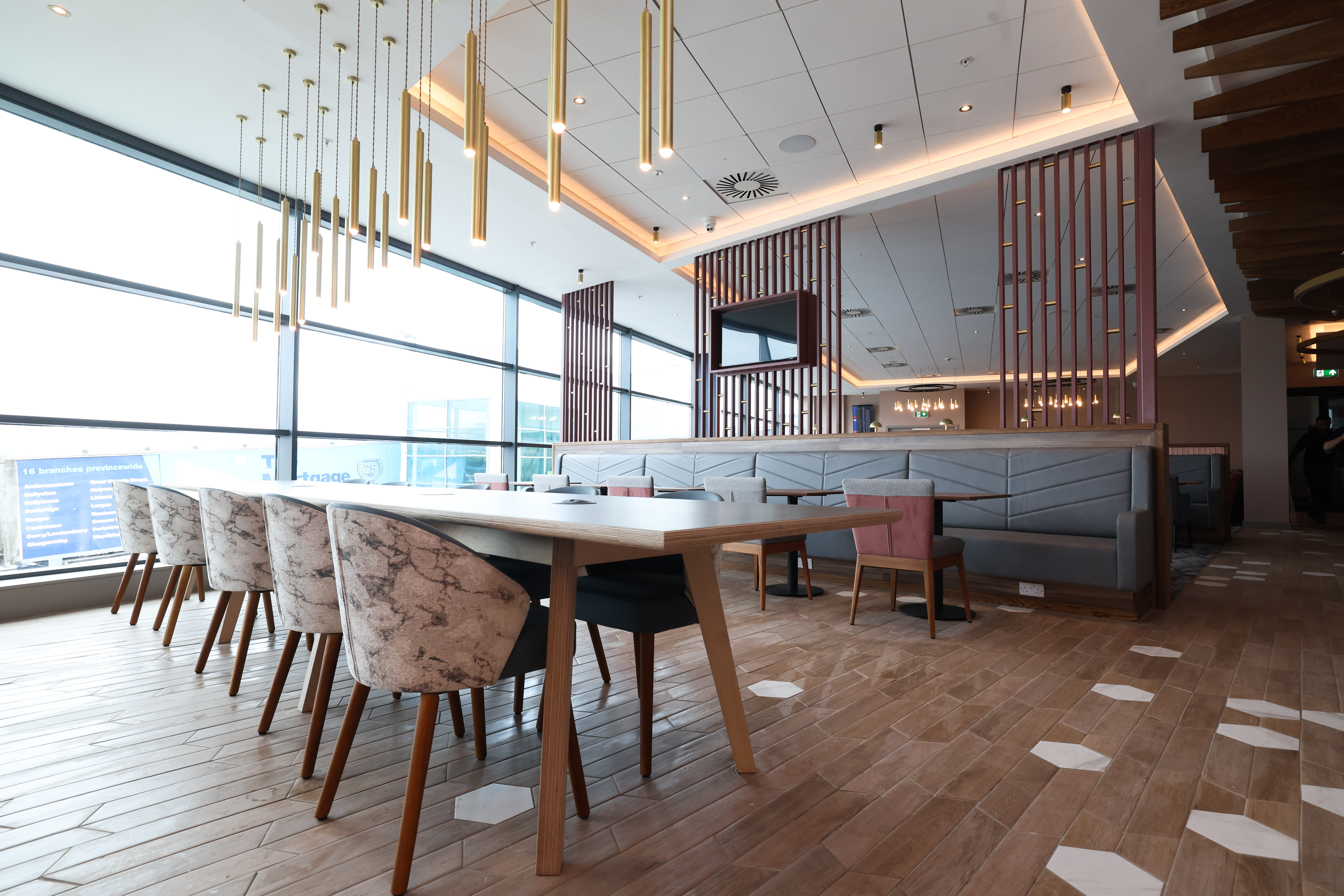 Spacious lounge dining area with wood floors and floor-to-ceiling windows at the Belfast Aspire Lounge.