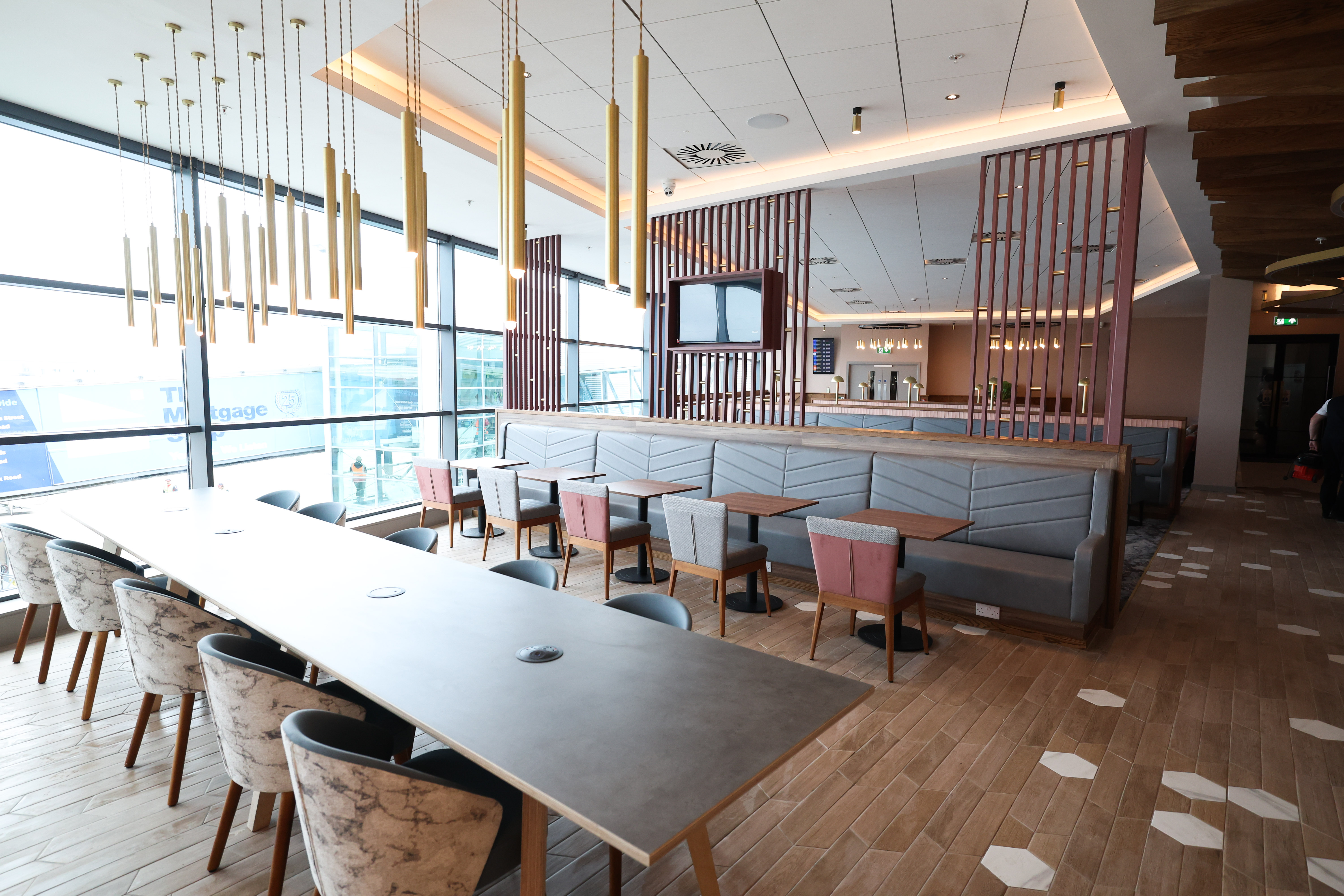 Spacious lounge dining area with wood floors and floor-to-ceiling windows at the Belfast Aspire Lounge.
