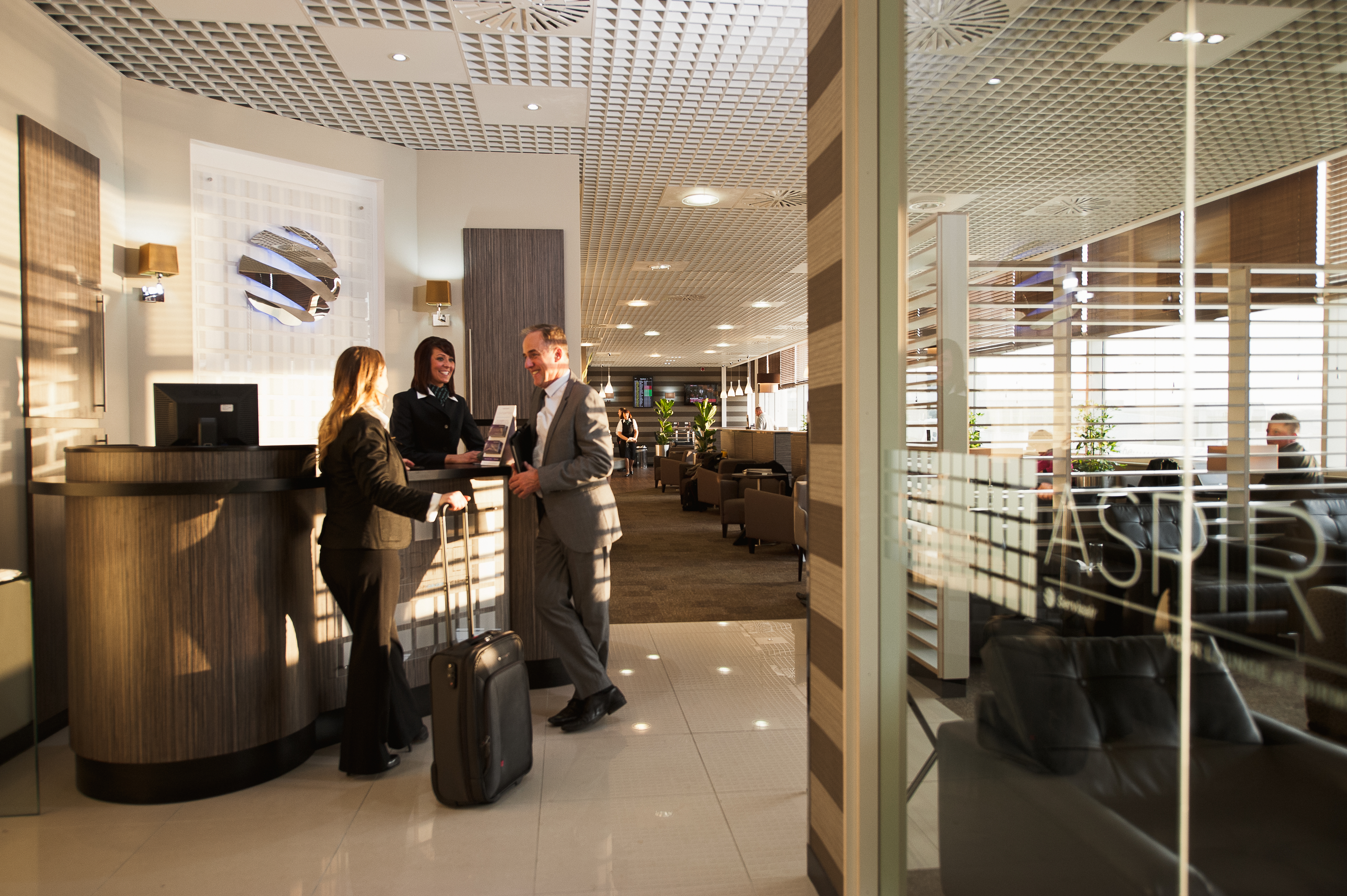 Two travellers at reception in the Birmingham Aspire Lounge.